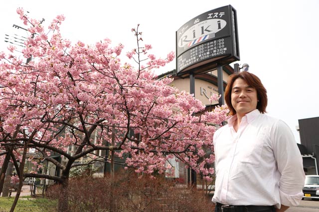 理容店「アートスペース リキ」の小林さんと満開になったとなりの緑地帯に立つ2本のカワヅザクラ