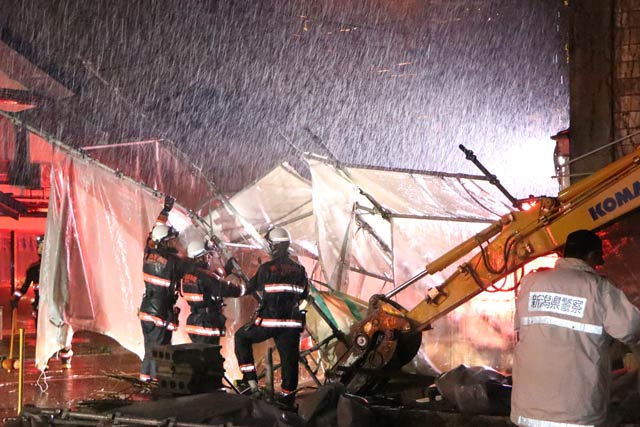 豪雨の中で工事用ネットを片付ける消防職員