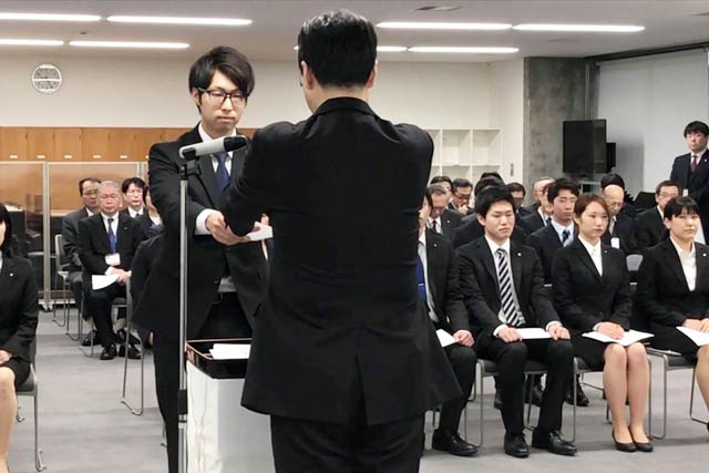 鈴木市長から新採用職員に辞令書を手渡す