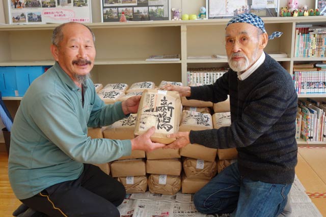 渡辺さん(左)から佐竹さんにコメを手渡す