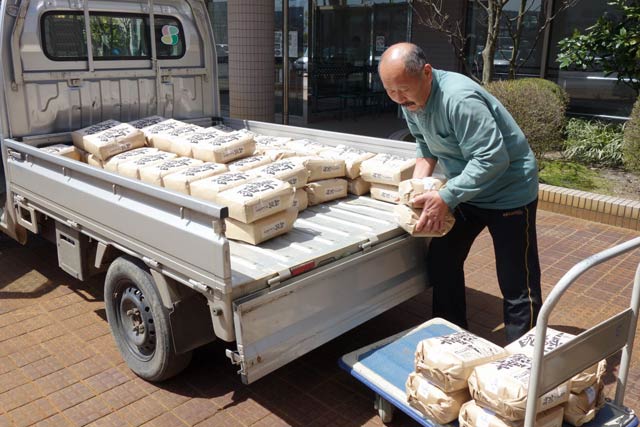 100袋のコメを軽トラから下ろす渡辺さん