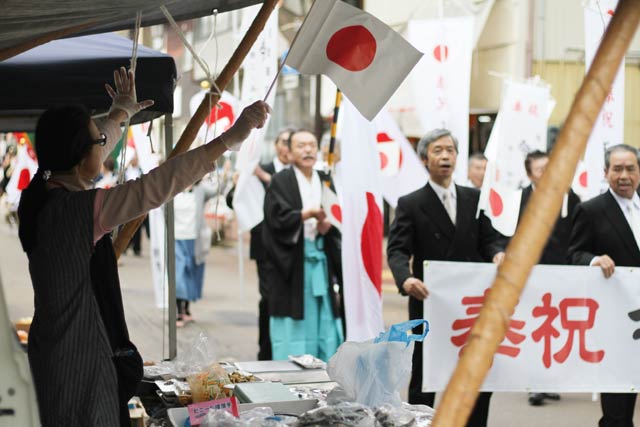 出店者も日の丸の小旗を振って祝福
