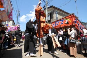 八幡宮を出高げたを振り上げて進む天狗