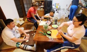 民泊の台所でみんなで調理するモンゴルのパラアーチェリー選手団