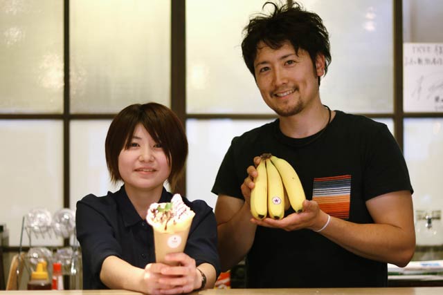 バナナ&チョコレートのクレープを手にTREEのメニュー開発担当の星田さん(左)とそれに使ったバナナを手にカネギフルーツの信賀店長