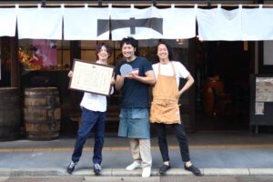 一ノ木戸商店街のTREEの前で左からTREEのマネジャー中川さん、カネギフルーツの信賀店主、TREEの今井さん