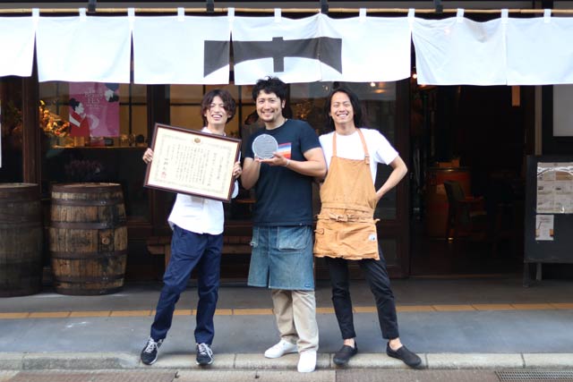 一ノ木戸商店街のTREEの前で左からTREEのマネジャー中川さん、カネギフルーツの信賀店主、TREEの今井さん