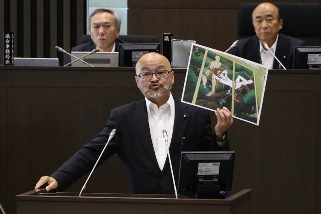 市議会で質問するタナカ氏