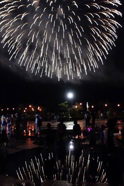 雨にぬれたアスファルトに映る花火