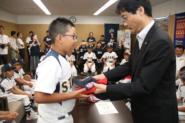 ヤクルトからの野球帽とユニホームを鈴木市長から南小スターズ選手一人ひとりに