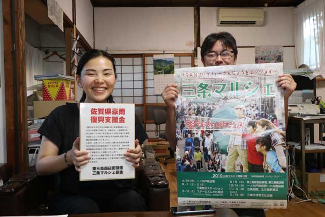 三条マルシェ事務局で三条マルシェのポスターと会場に設置する「令和元年8月佐賀県豪雨災害義援金」の募金箱