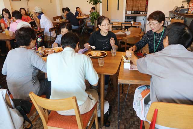 三条マルシェを訪れてエアコンの効いたレストランで食事する只見町の八十里越体験ツアー参加者