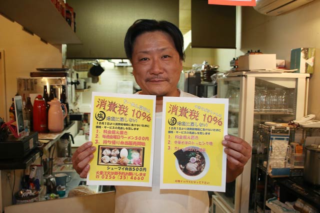 酒場カンテツで「増税に屈しない」サービスのちらしを手に関本社長