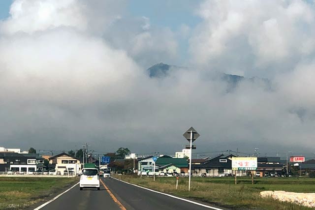 朝方に雲から頭だけ出した弥彦山