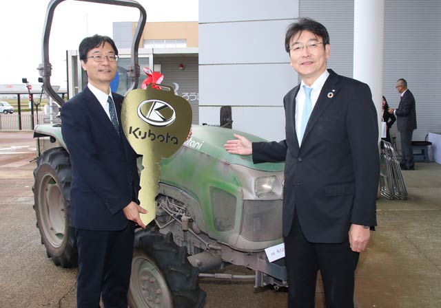 寄贈を受けたトラクターの前で鈴木燕市長(左)とクボタの飯塚執行役員