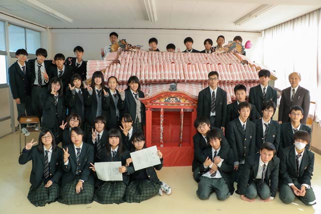 完成した段ボール製首里城と記念写真を撮る吉田高校2年1組