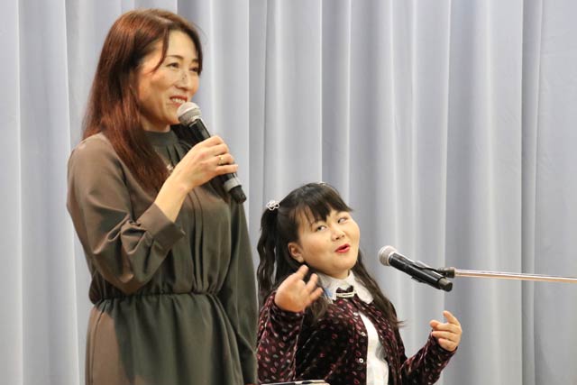 長岡市立太田小中学校のステージに立つ佐藤絵美さん、ひらりさん親子