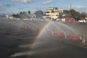 青空の消防出初式の放水訓練で虹