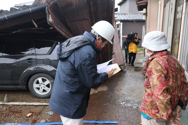 罹災証明書発行の申請手続きを付近住民に案内する燕市職員