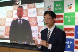 寄付のリモート授与式で鈴木市長と映像はアイモバイルの加藤本部長
