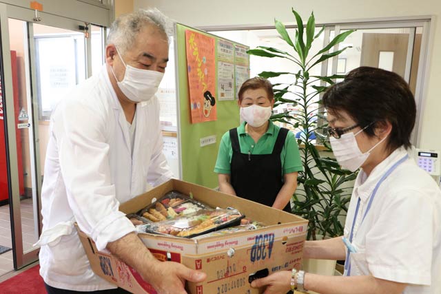 鈴木園長に弁当を手渡す清みずの阿部さん(左)