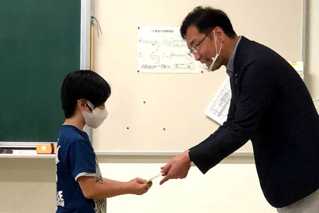 国定市長から児童代表に快段目盛を手渡す