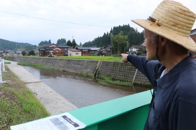 クマがよじ登ろうとした鹿熊川の斜面を指さす五十嵐自治会長