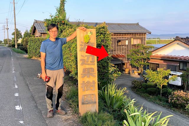渡辺果樹園の入り口の看板と経営者の渡辺さん