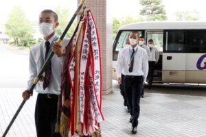優勝旗を手にした椿主将を先頭に加茂市役所で拍手に迎えられる選手