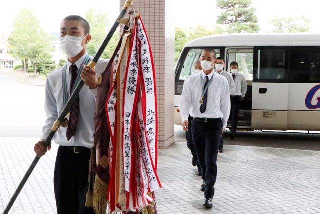 優勝旗を手にした椿主将を先頭に加茂市役所で拍手に迎えられる選手