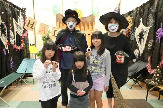 しらさぎ荘のハロウィーンの撮影コーナーの前で恐怖の目玉ゼリーをもらった子どもたちがコスプレのスタッフと記念撮影