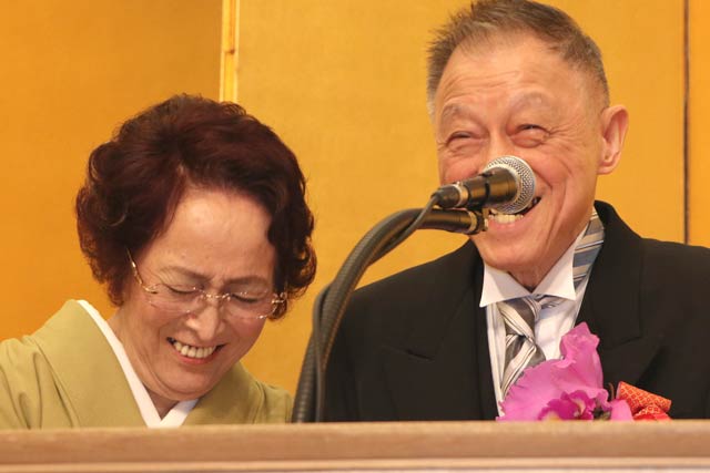 叙勲受章記念祝賀会で壇上で大笑いするふたり