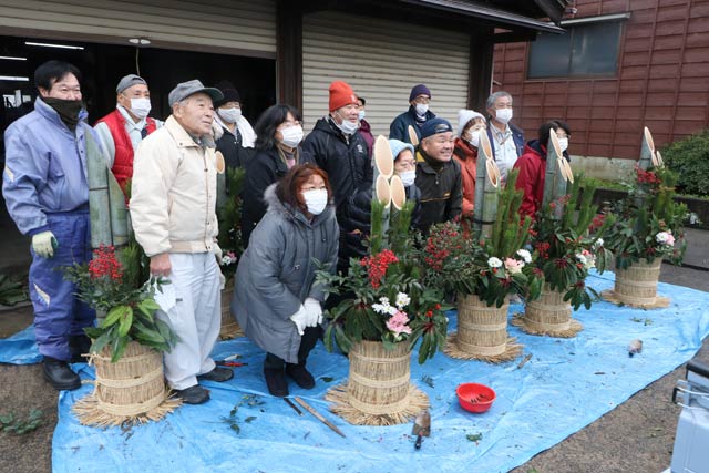 西本成寺有志会が完成した門松と並んで記念撮影