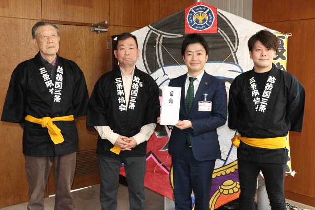 裏館小学校に寄付する凧を背に右から2人目の滝沢市長を囲んで左から三条凧協会の高橋顧問、須藤会長、結城副会長