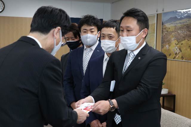 燕商工会議所青年部の鈴木会長（いちばん右）から絵本『おかねってなぁに？』の寄付目録を受け取る鈴木燕市長（いちばん左）