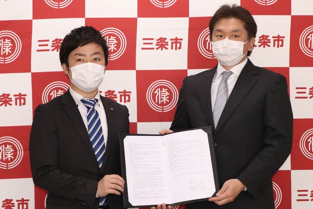 調印した工業流通団地分譲の売買契約書を手に滝沢市長(左)と伊藤社長