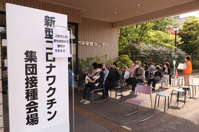 三条市の集団接種会場の順番待ちは正面玄関の外にいすを並べて