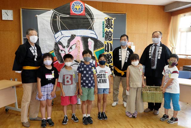 裏館小学校で六角巻凧の贈呈式、前列は3年生、後列は左から高橋さん、須藤さん、太田さん