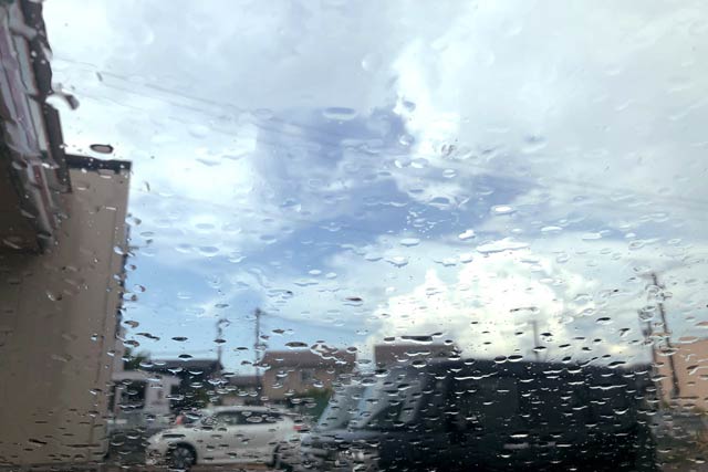 雨に濡れた車のガラスの向こうに青空