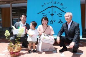 道の駅 たがみの前で左から馬場駅長、10万人目の大野さん親子、佐野町長