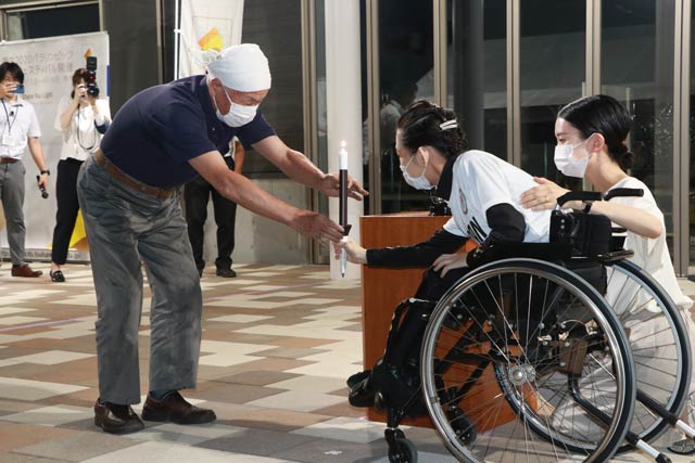 玉川さん(左)から坂田さんに炉の火を移したろうそくの火を手す