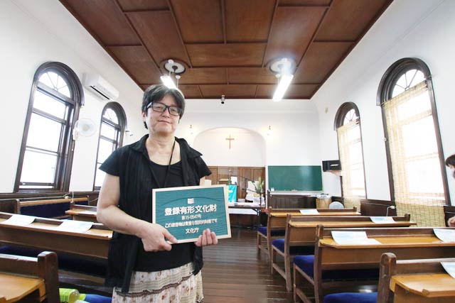 日本基督教団燕教会で登録有形文化財プレートを手に田中牧師
