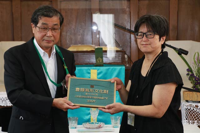田中牧師に登録有形文化財プレートを手渡した山田教育長