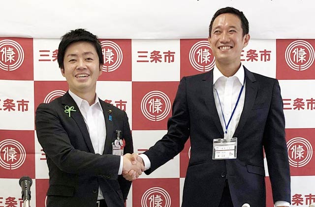 滝沢市長(左)と握手する三条市CMOに就任した澤さん