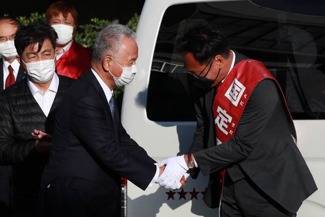 がっちり握手する甘利幹事長と国定氏 