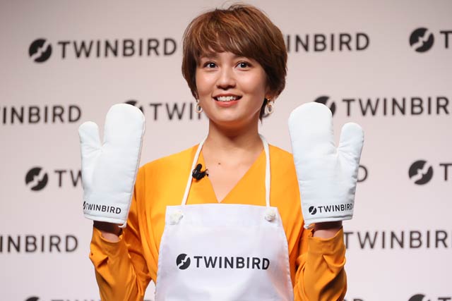 新しいロゴデザインのエプロンとミトンを着けた和田明日香さん