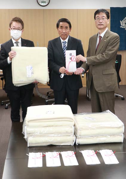 山下家具店が寄付した毛布と山下社長(中央)と鈴木市長(右)