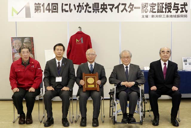 中野さんにマイスターブルゾンをかけるにいがた県央マイスターズクラブの川崎会長