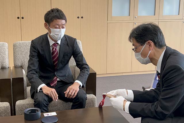 金メダルを手に取る鈴木市長