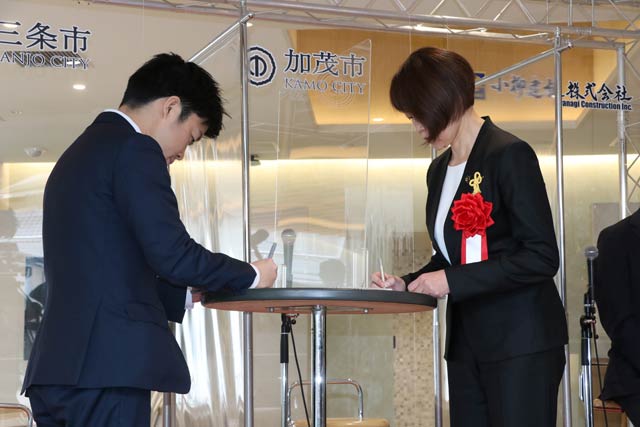 協定書にデジタル書名する滝沢三条市長と藤田加茂市長
